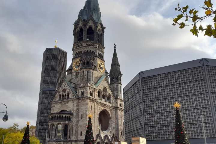 a statue in front of a tall building with Kaiser Wilhelm Memorial Church in the background